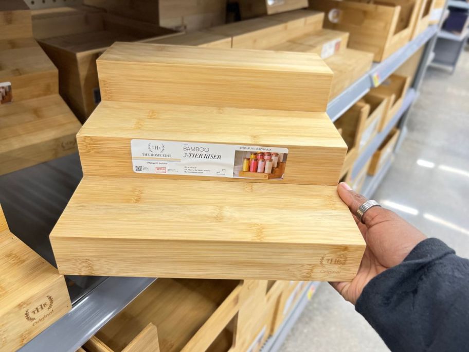 hand holding The Home Edit 3-Tier Bamboo Riser in store