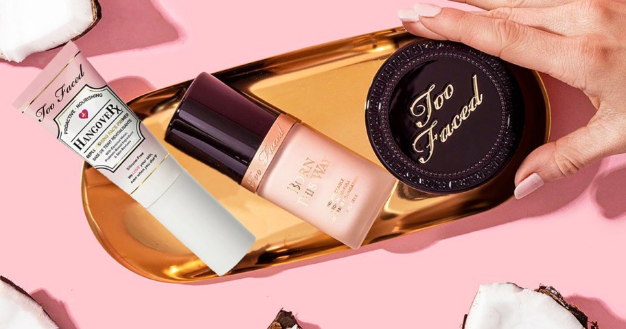 hand grabbing too faced products from gold tray