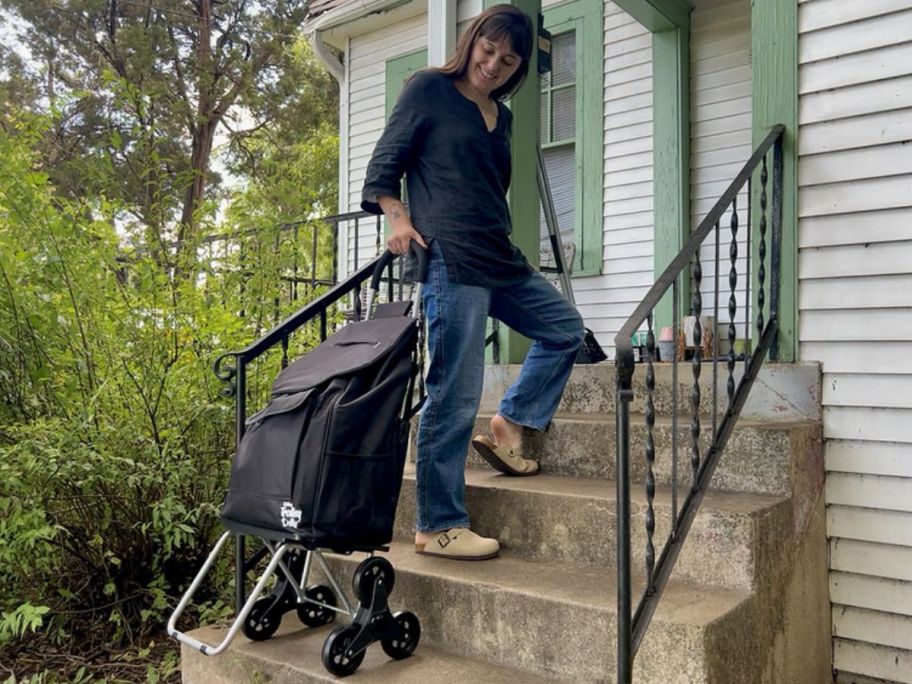 a woman rolling a trolley dolly up the front steps of a house