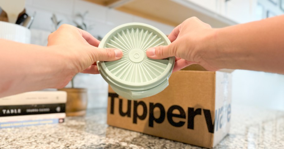 person pressing lid of green tupperware bowl