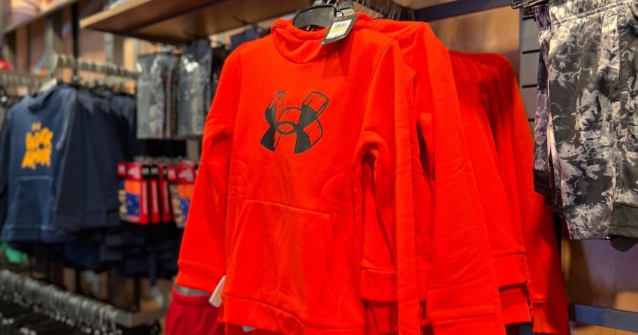 A red Under Armour Boys Hoodie Hanging on a rack at the Under Armour store