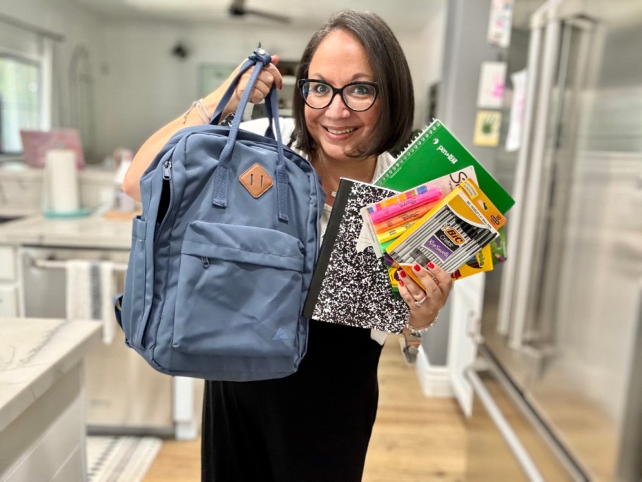 Woman holding up a backpack and school supplies she got from Walmart Plus