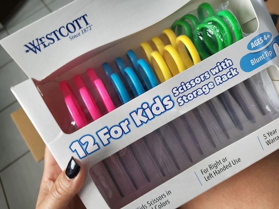 A person holding a Westcott 12-Pack Kids Scissors