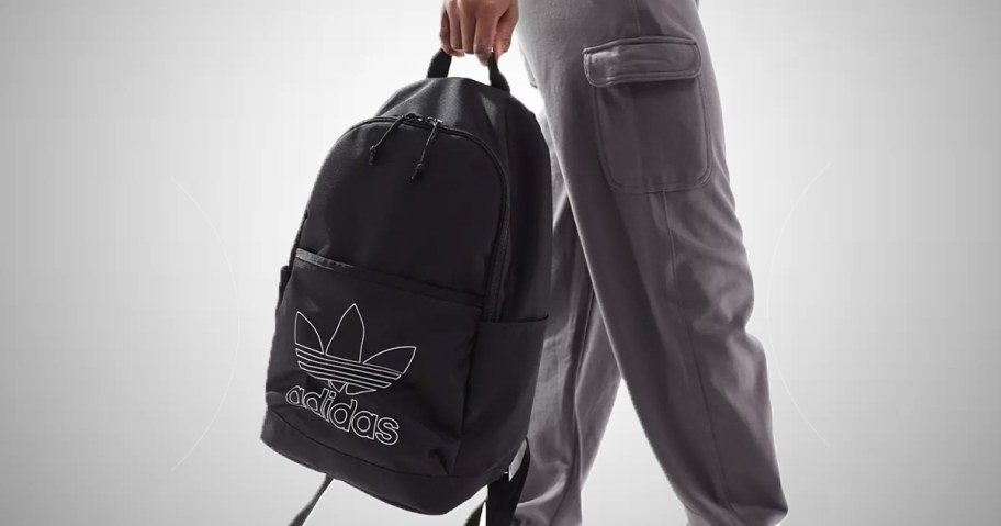 person holding black adidas backpack