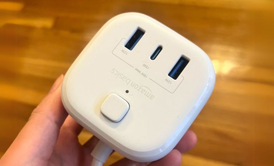 A person holding an AmazonBasics Power Strip Cube 3 Outlet 3 USB Ports