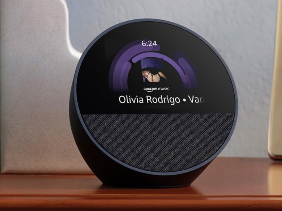 black Amazon Echo Spot device with a display screen playing music by Olivia Rodrigo