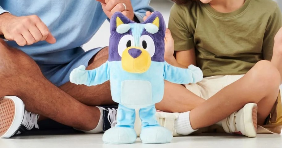 bluey plush sitting in front of child and dad