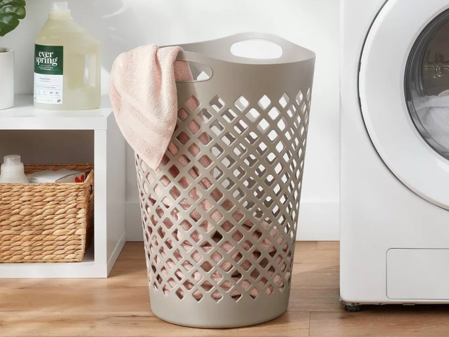 gray plastic hamper with towels next to washer