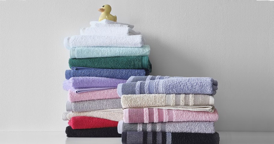 multiple colored towels stacked with rubber duck sitting on top 