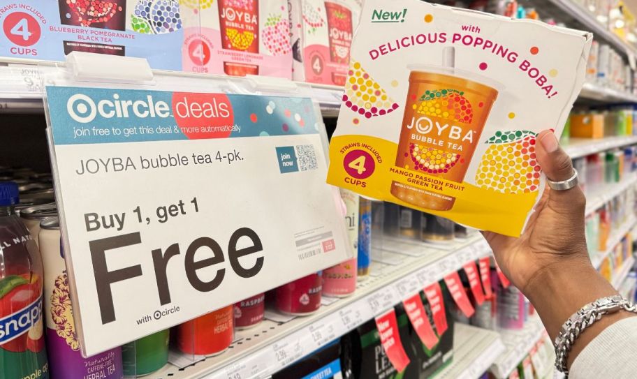 a womans hand grabbing a 4 pack of joyba tea from a store shelf