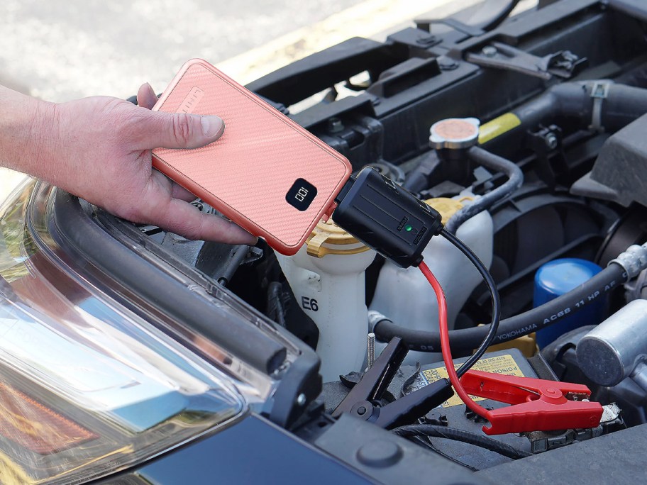 hand holding orange battery boost connected to cart battery