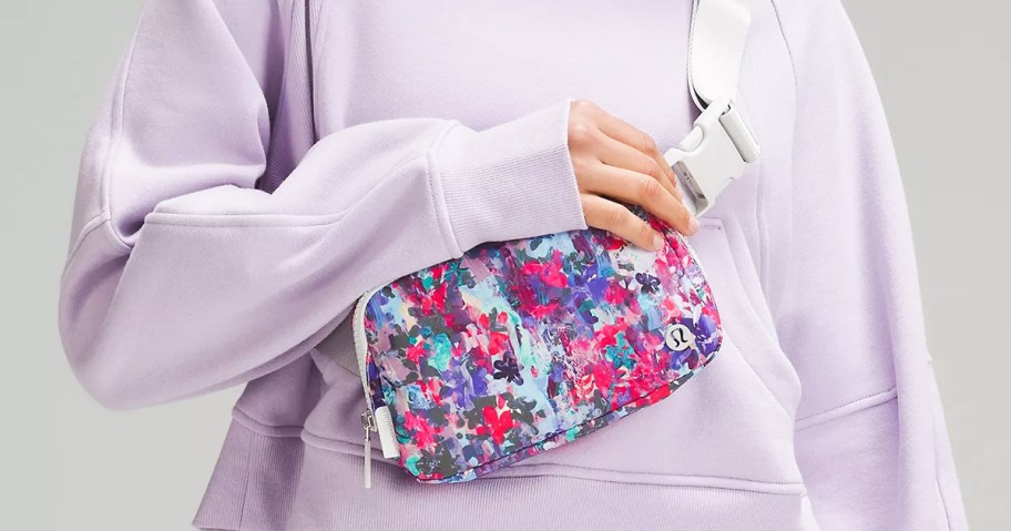 woman in lilac sweatshirt with floral print belt bag