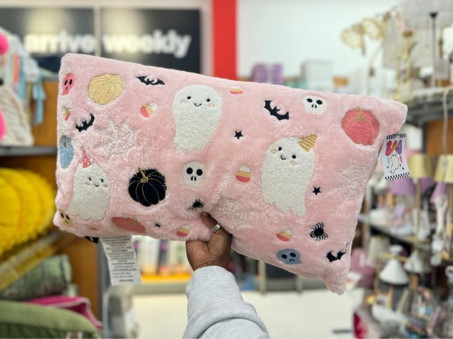 a pink lumbar throw pillow with ghosts and pumpkins on it