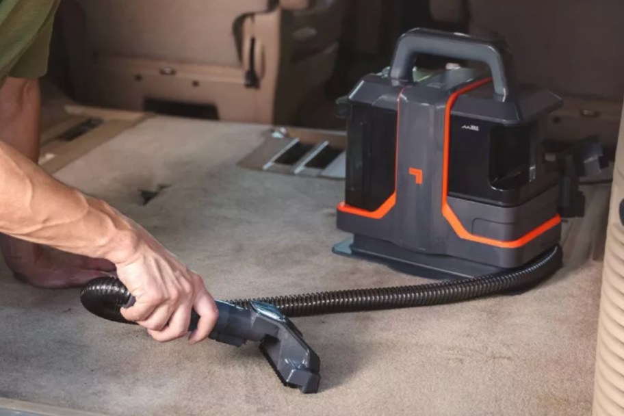 hand cleaning back of car with portable vacuum