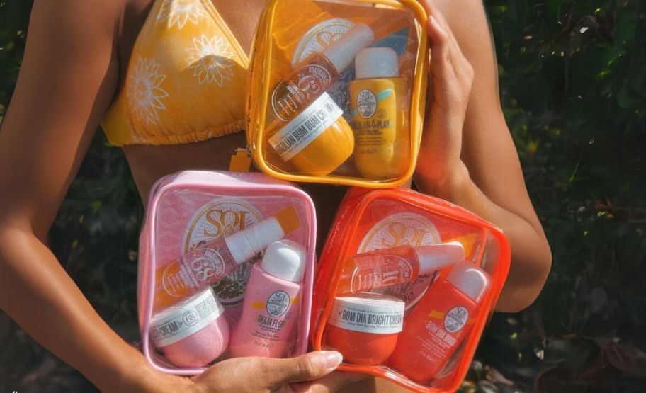 a woman holding 3 3piece sol de janeiro jet set kits.