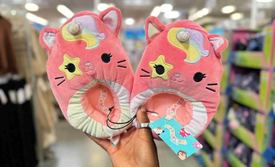 a woman's hand holding a pair of caticorn squishmallows kids slippers