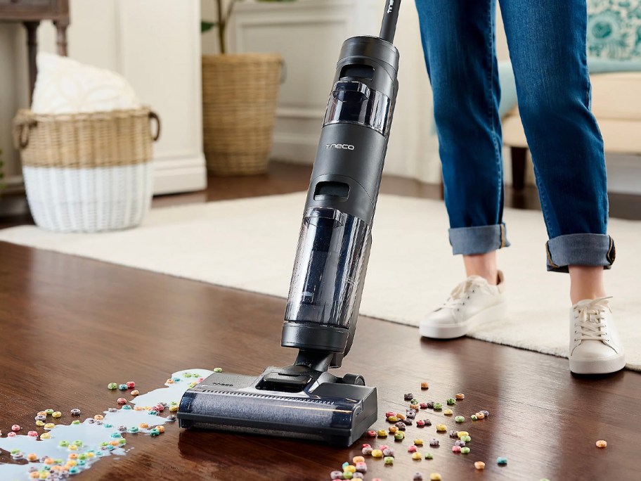 person using black and silver tineco vacuum to clean spilled milk 