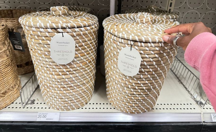 two small rattan waste baskets with lids on store shelf