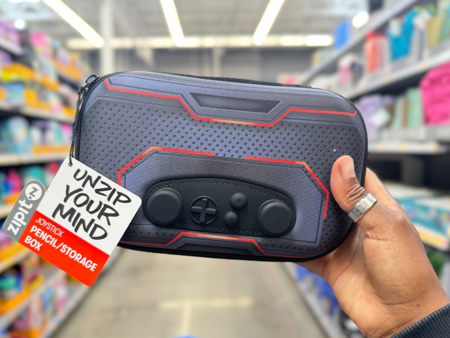 hand holding a joystick controller shaped pencil case in a store aisle