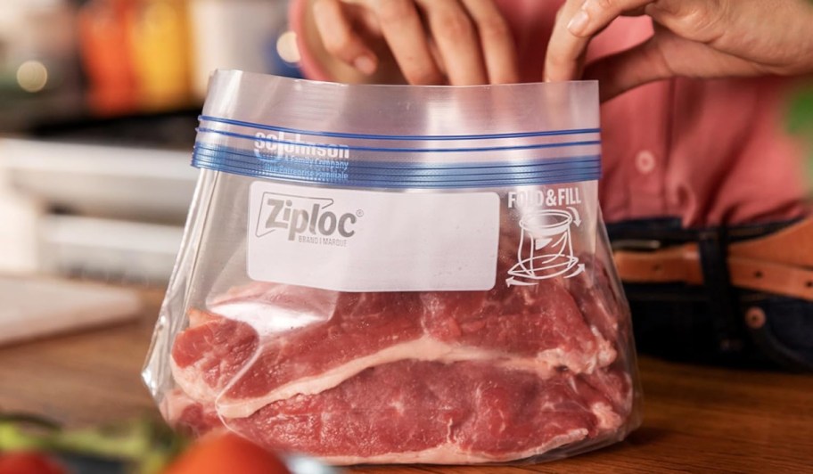 person placing a steak into a ziploc bag