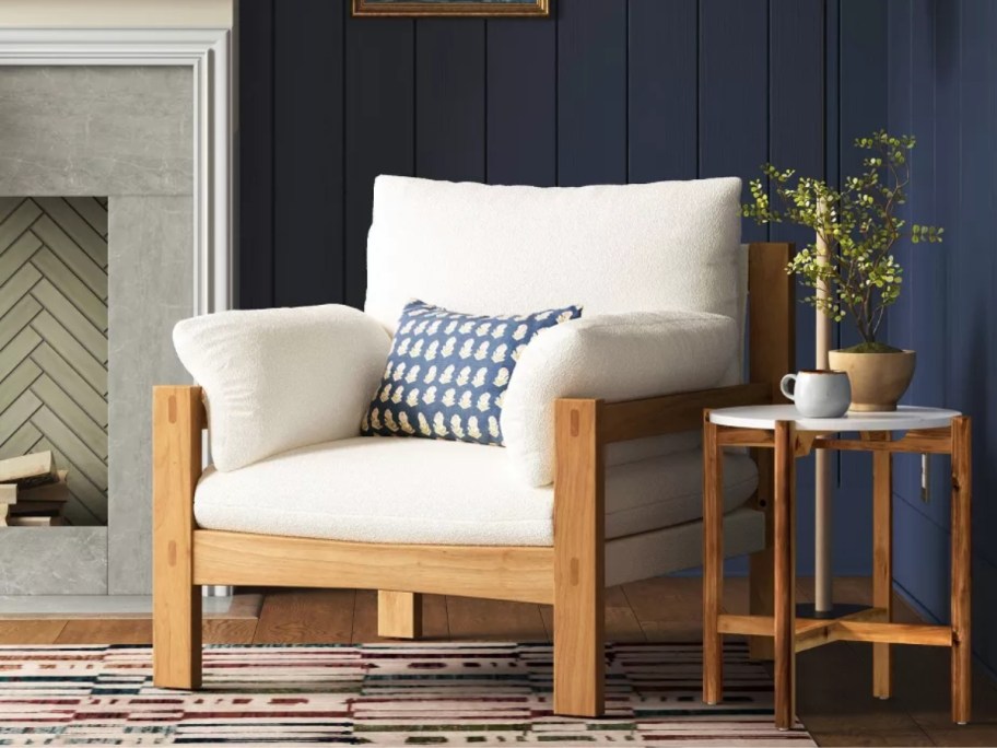 wood accent chair with cream cushions and a navy throw pillow in a living room