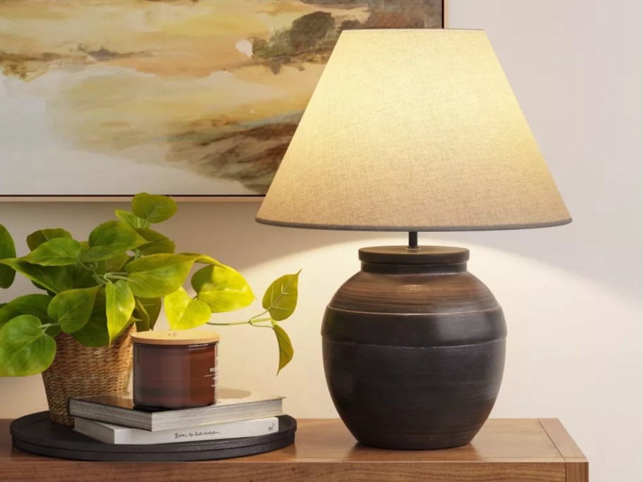 large brown ceramic table lamp with a linen shade on a console table