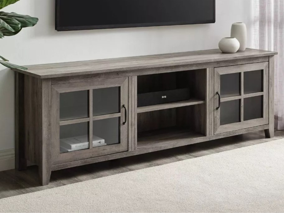 large grey TV stand with a TV on the wall above it in a living room