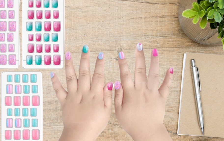 girls hands with press on nails on wood table