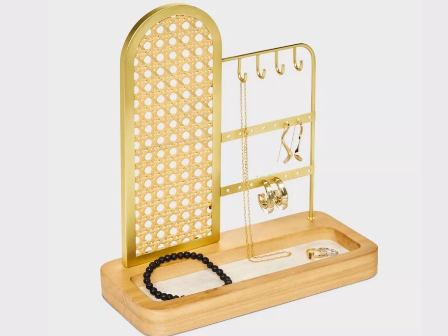 rattan and metal jewelry organizer stand with jewelry on it