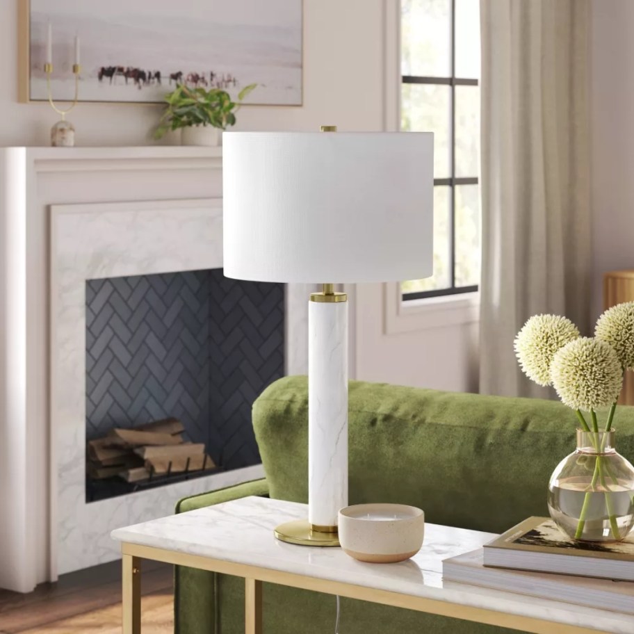 large white table lamp with a marble base and white shade on a console table in a living room