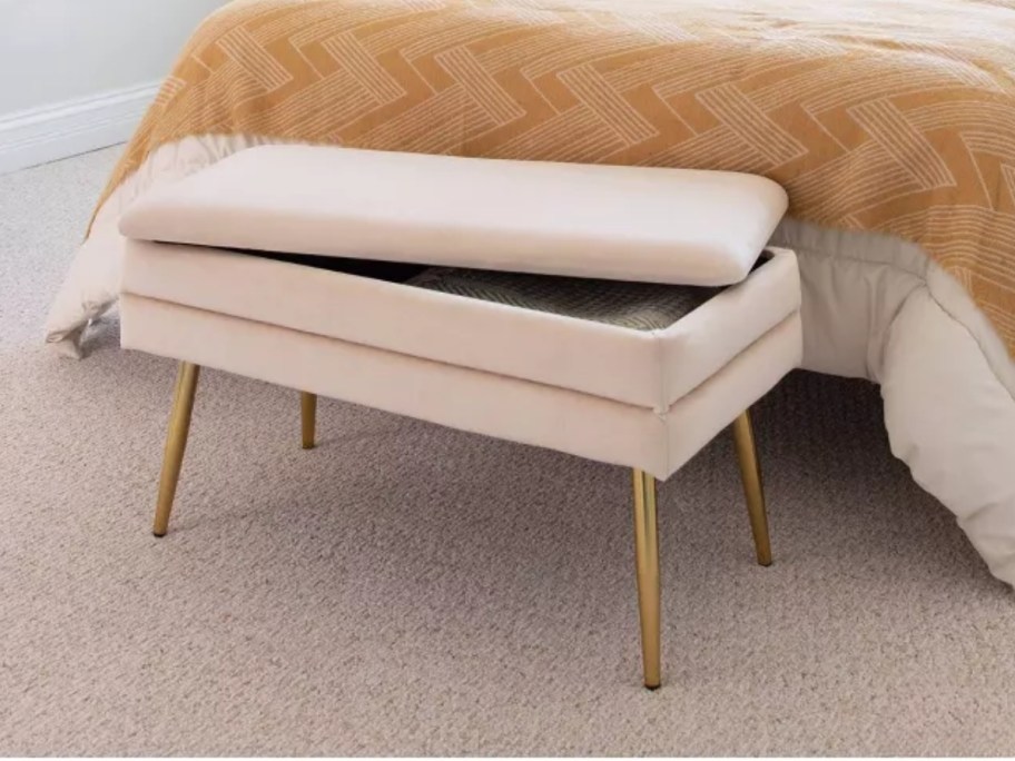 light pink velvet lift top storage bench at the foot of a bed