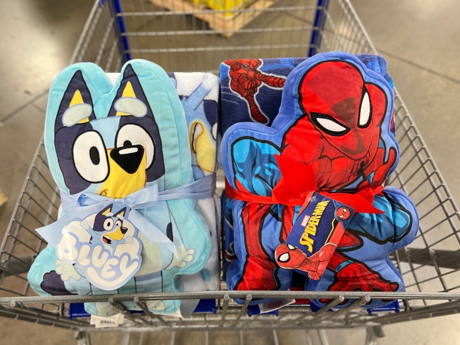 a Bluey Pillow and Throw Blanket and Spiderman Pillow and Throw Blanket in a Sam's Club cart