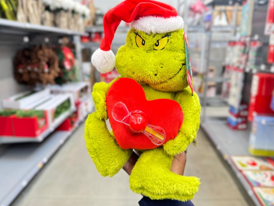 Animated grinch with heart in front of him in womans hand at the store