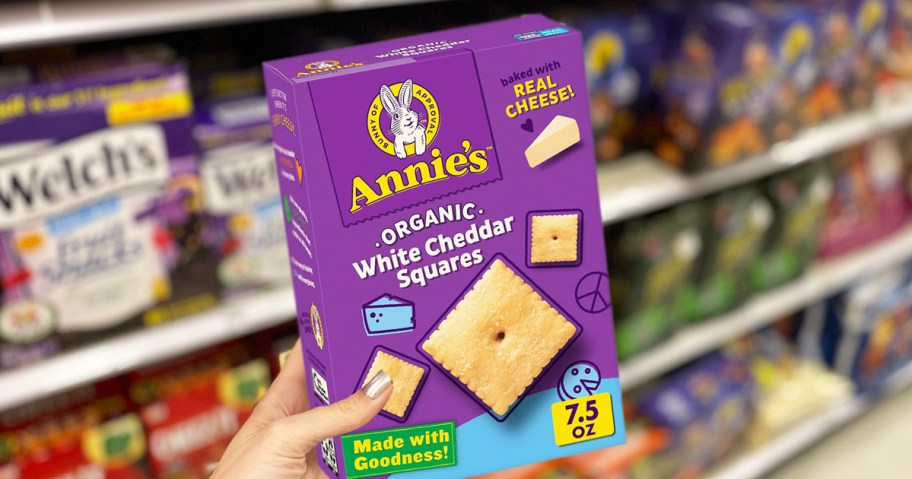 hand holding a box of Annie's Organic White Cheddar Squares in store