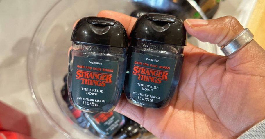 Hand holding two Stranger Things The Upside Down Scented Pocketbac Hand Sanitizers from Bath & Body Works