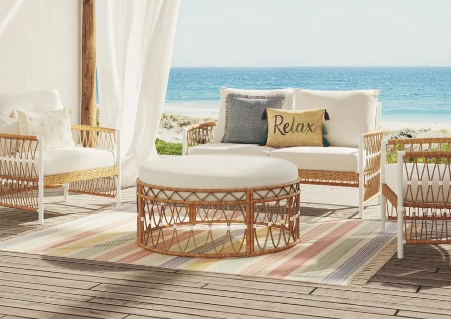 a round wicker ottoman on a seaside patio with a wicker setee 