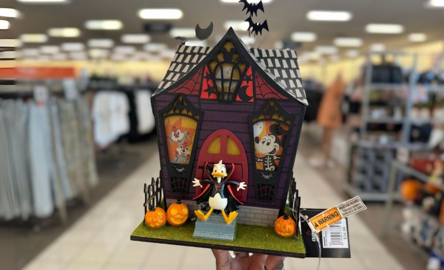 a womans hand holding a donald duck halloween house