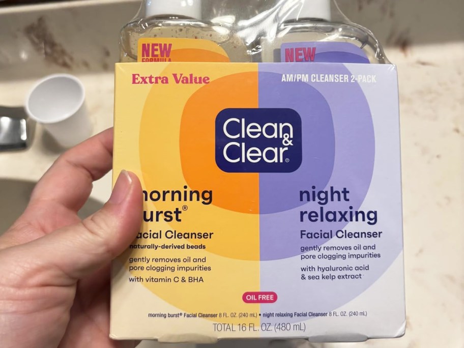 hand holding up Clean & Clear Facial Cleansers Set in bathroom