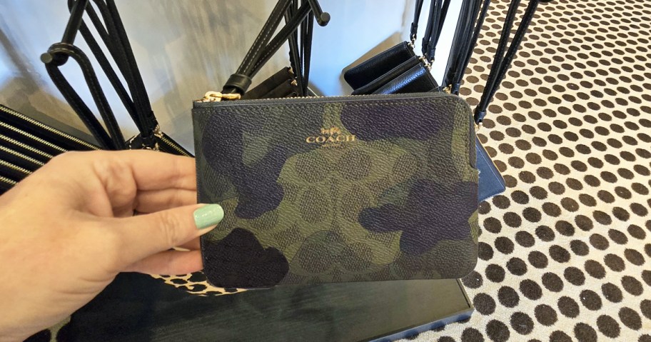 woman holding a camo print wristlet in store