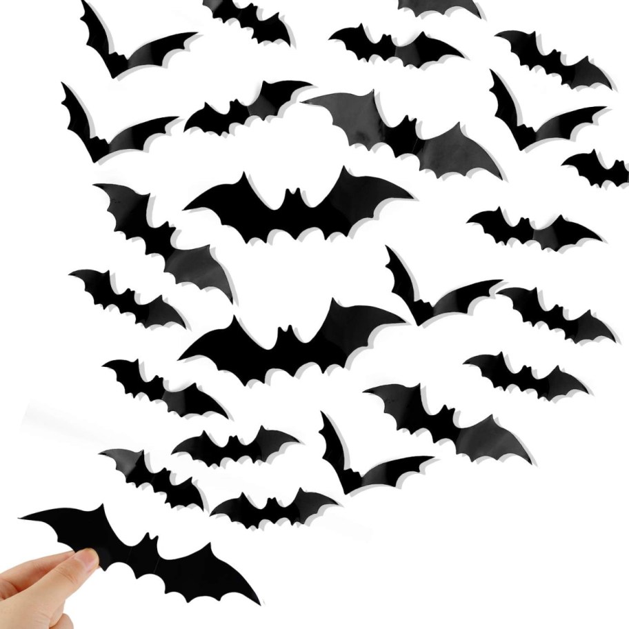 Hand placing faux bats on the wall as Halloween decor