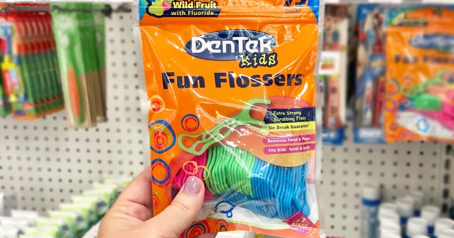 hand holding up an orange bag of DenTek Kids Fun Flossers in store