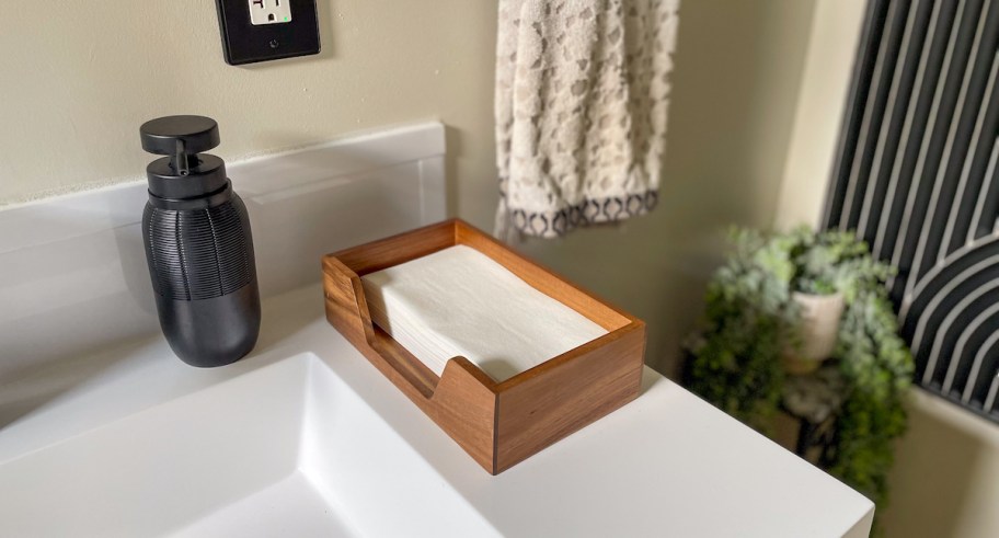 disposable hand towel napkins in wood holder on bathroom sink