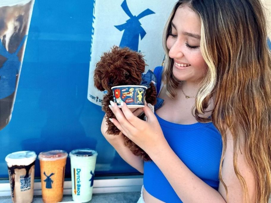 Teen girl feeding a small dog a pup cup from Dutch Bros