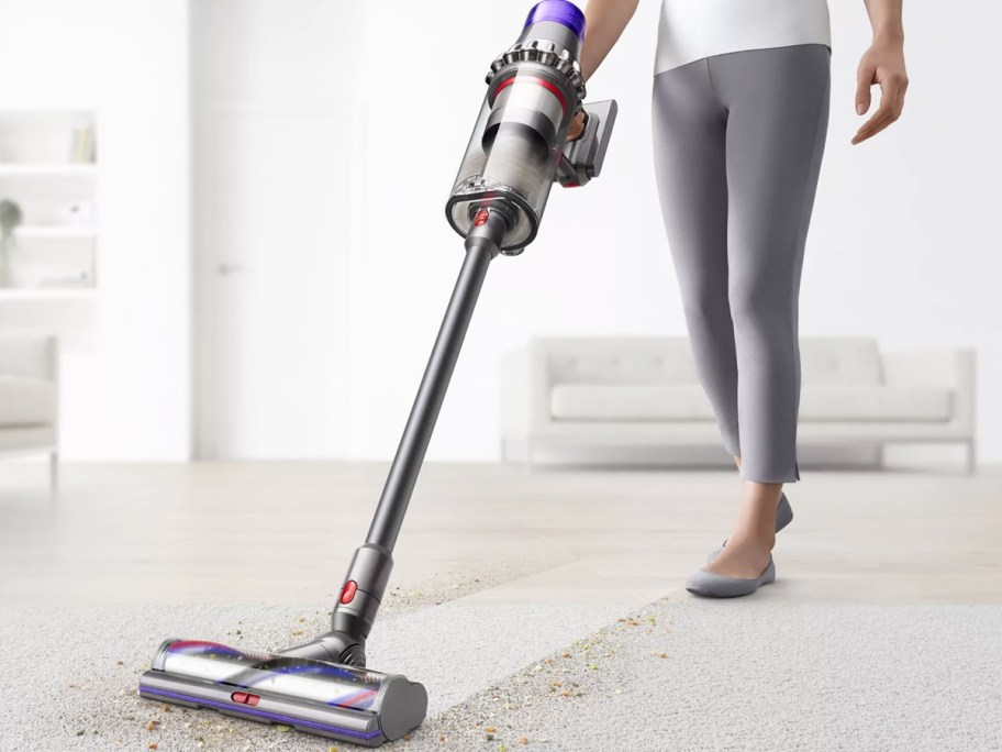 woman cleaning carpet with dyson stick vacuum