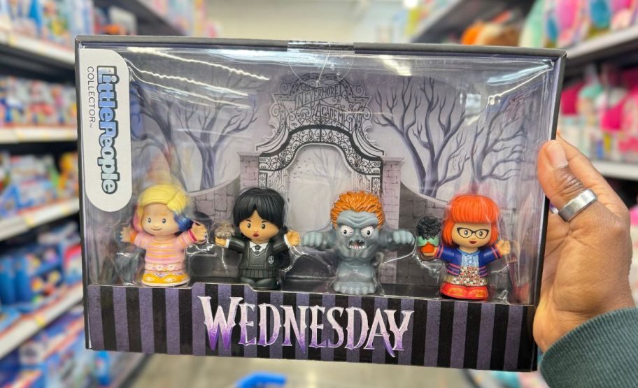 a womans hand holding a Little Peoples Wednesday collectors set.