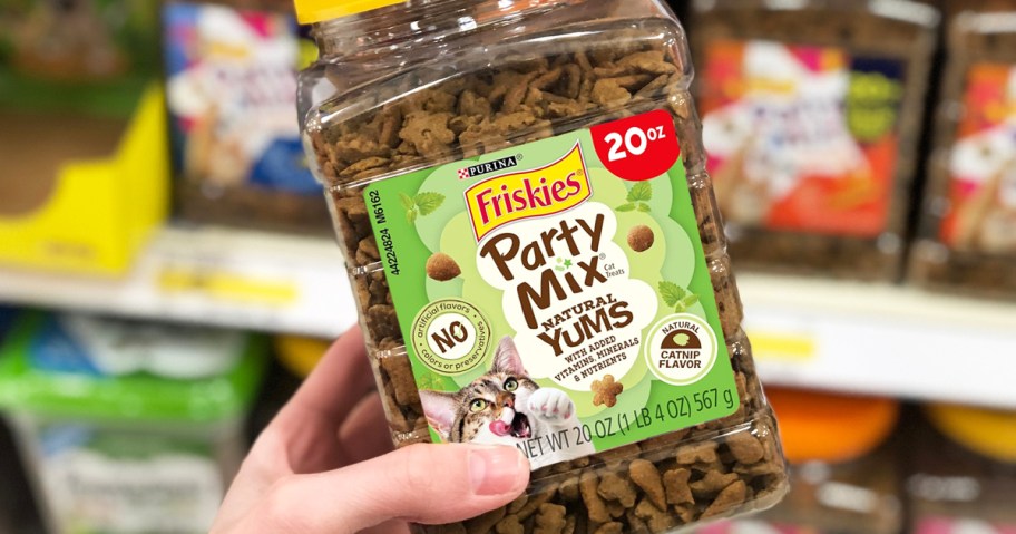 hand holding a container of Friskies Party Mix Cat Treats in store