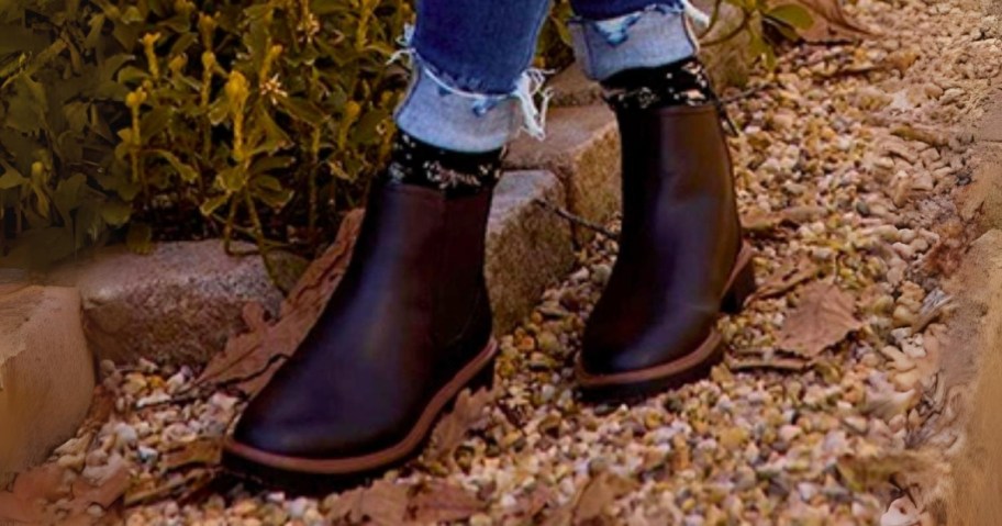 woman walking outside wearing black Chelsea style boots with cuffed jeans