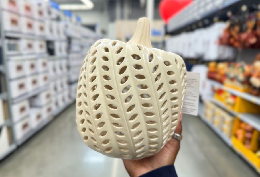 a womans hand holding a white led ceramic pumpkin