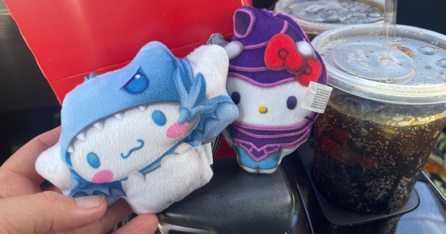 2 hello kitty happy meal toys next to drink inside car