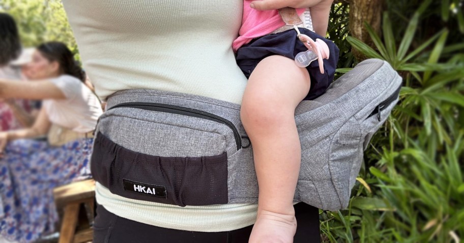 woman holding baby on a hip carrier